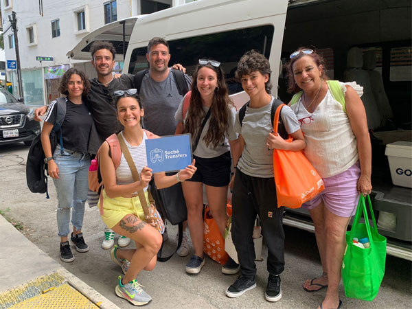 Grupo de viajeros recibido por Sacbe Transfers en el aeropuerto junto a sus camionetas